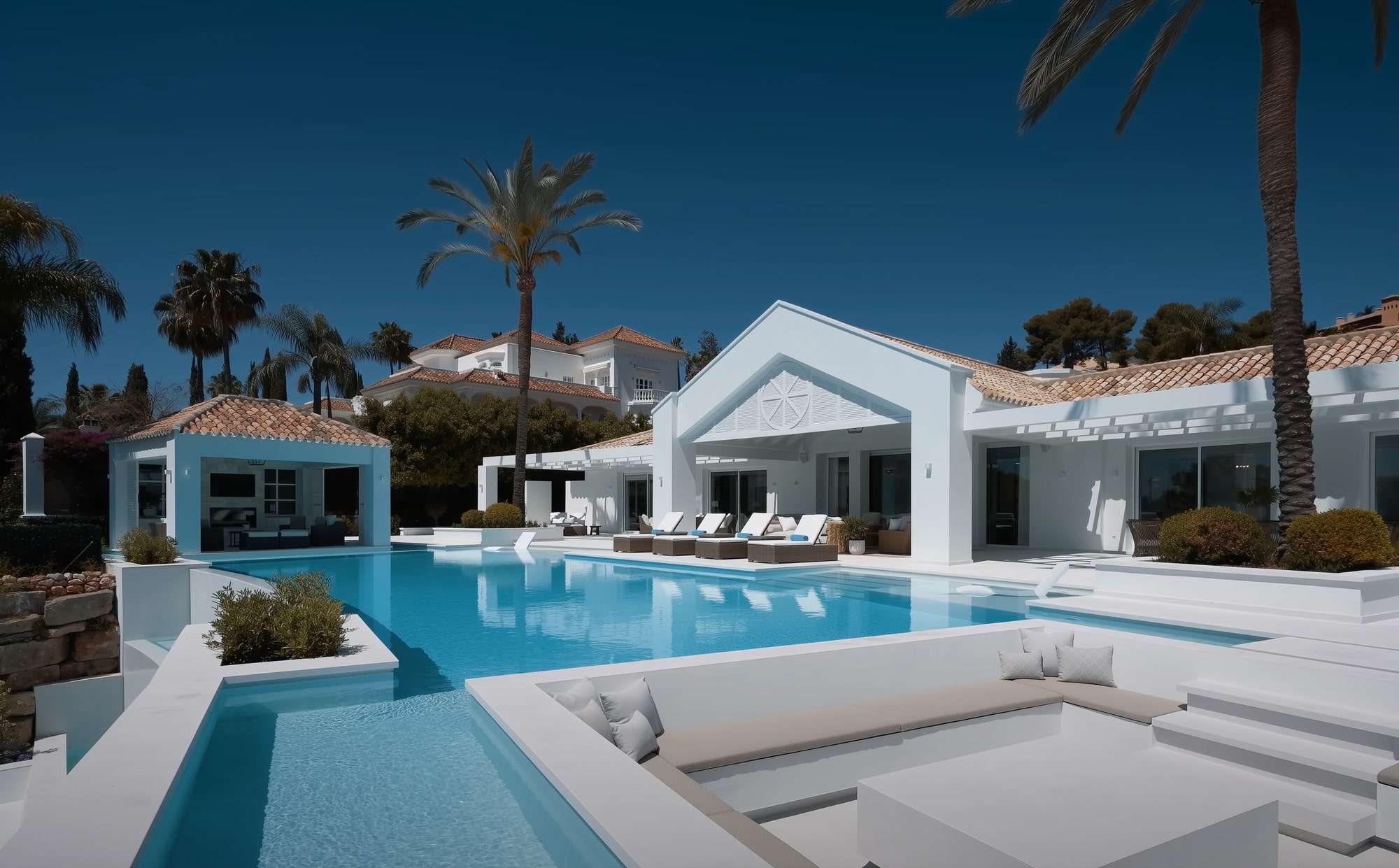 Infinity pool reflecting Mediterranean skies and villa exterior