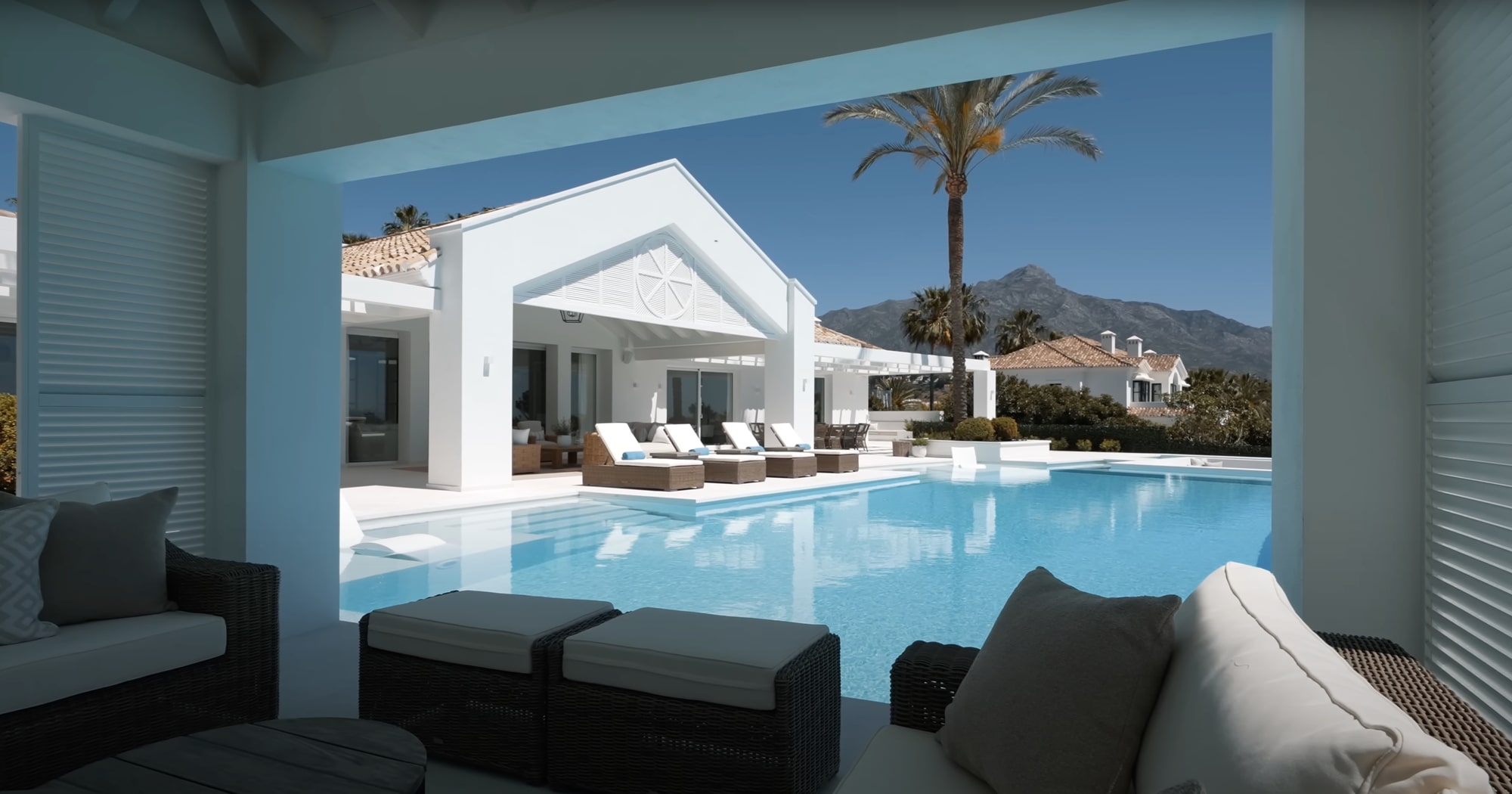 Covered lounge area beside the pool with elegant furnishings