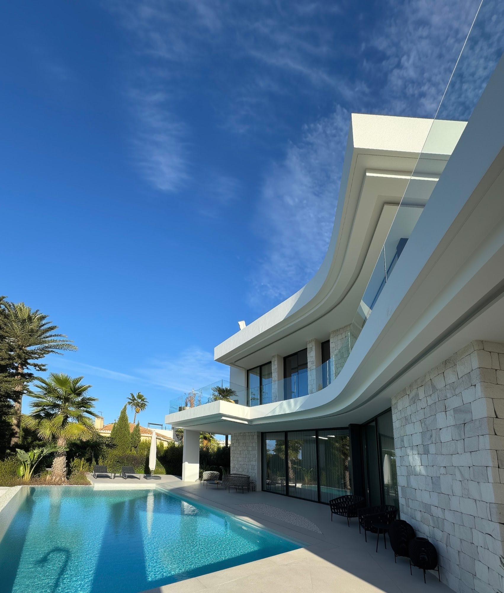 M94 – villa façade with flowing curved terraces and natural stone