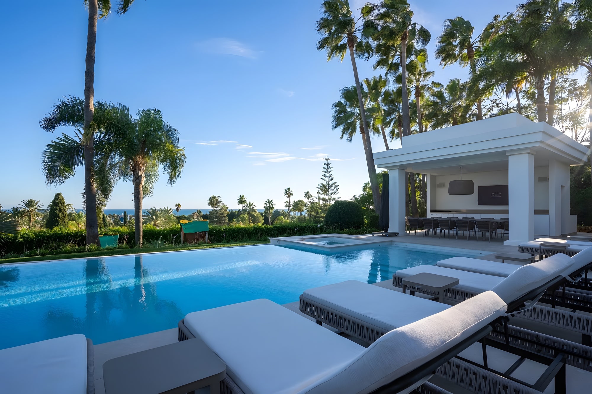 Outdoor dining area surrounded by palm trees and pergola