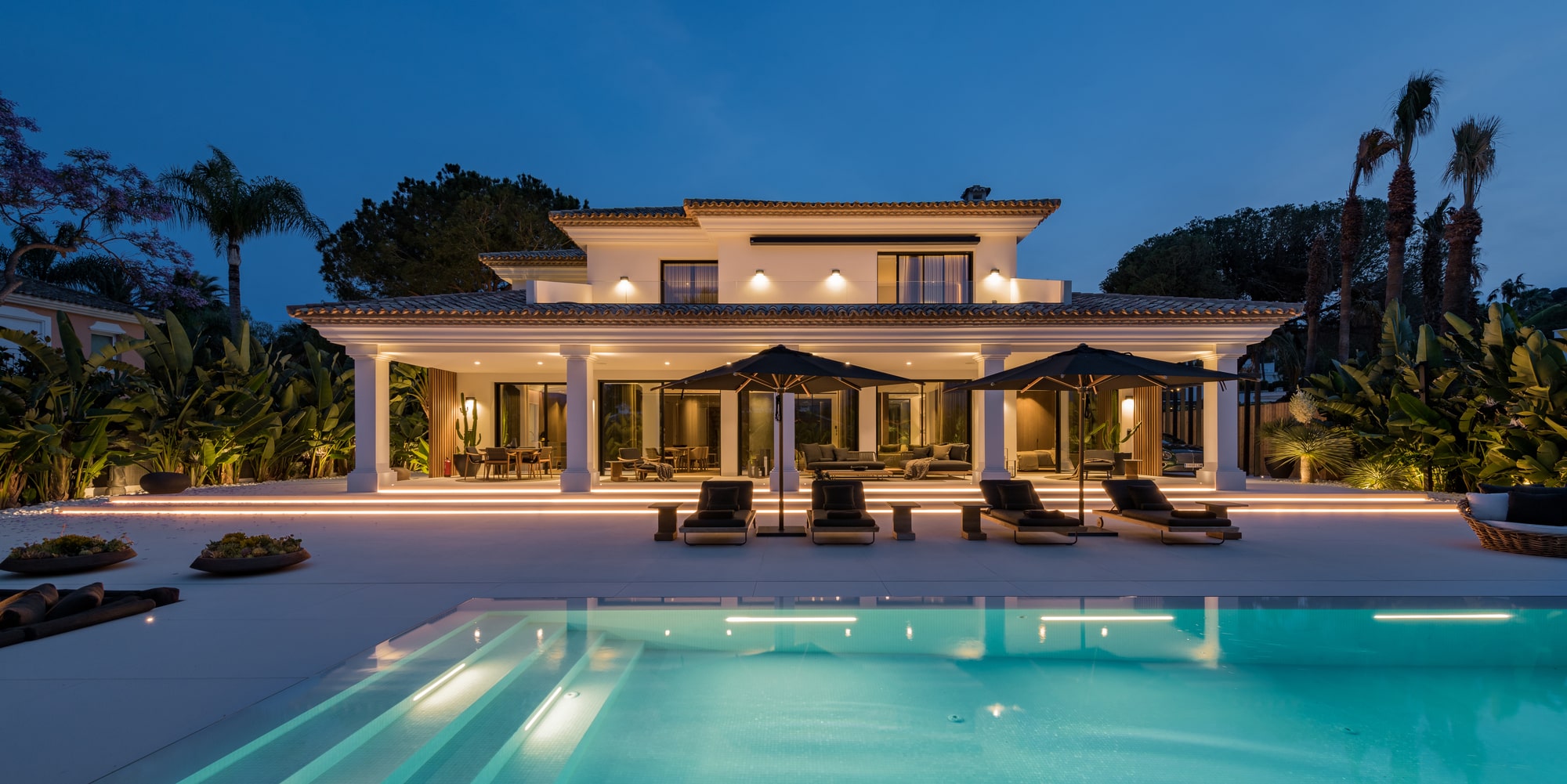 Twilight view of VILLA ZARINA with ambient pool lighting and refined landscaping